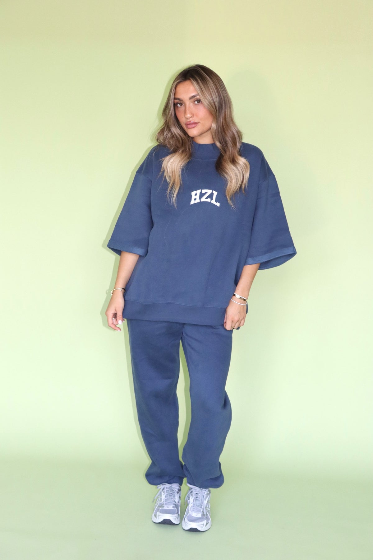 Model wearing a navy HZL mockneck top with matching pants and white sneakers