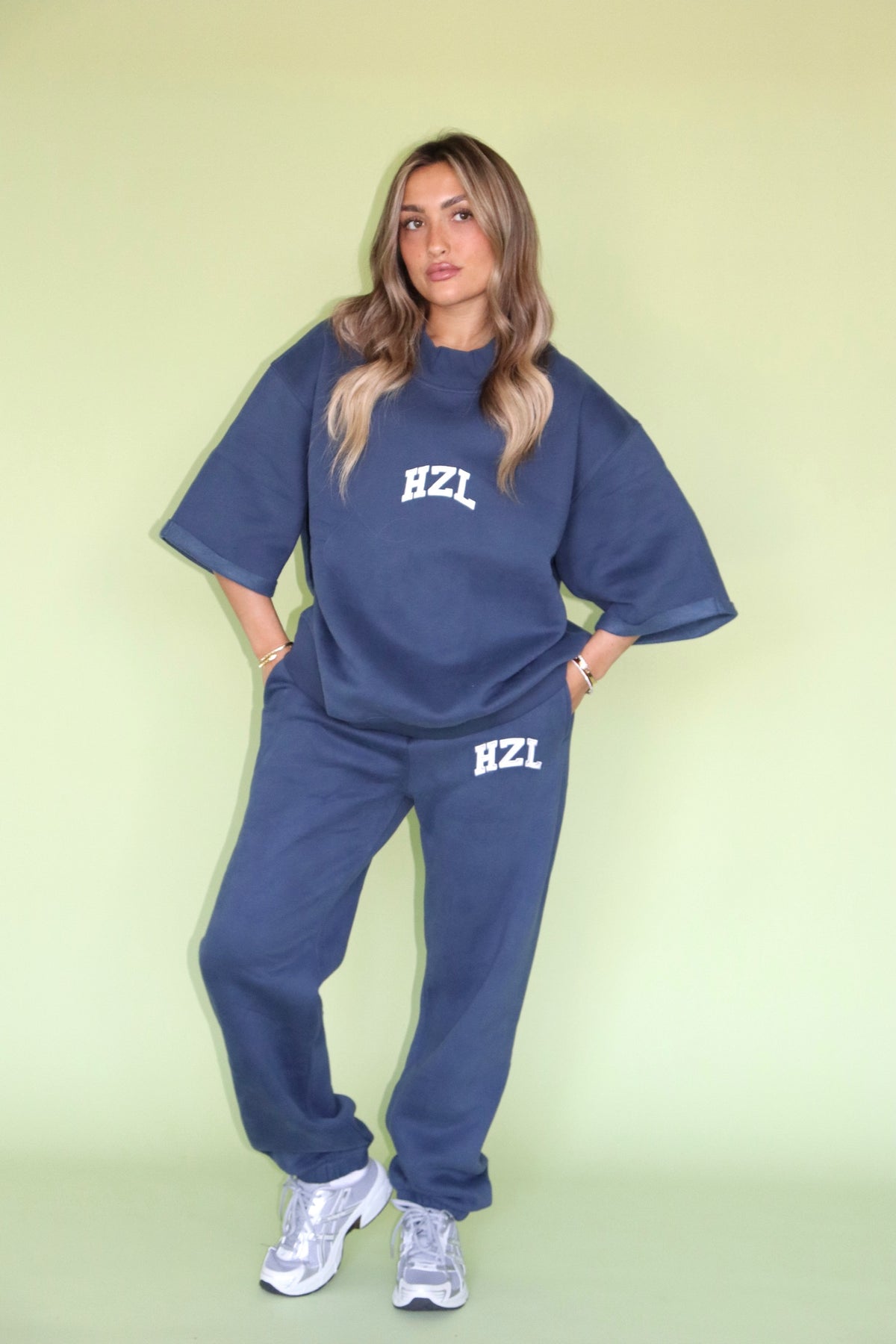 Model wearing navy HZL joggers with a matching oversized sweatshirt and white lettering