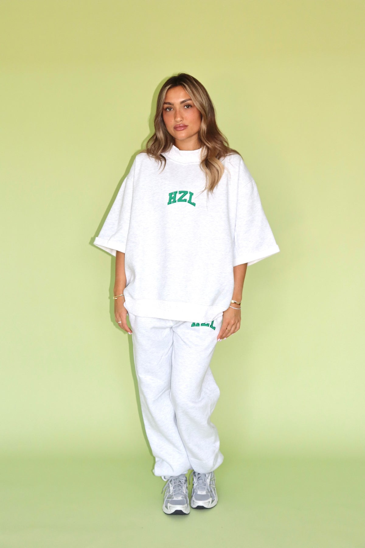 Model wearing a white HZL short sleeve mockneck with matching joggers and sneakers