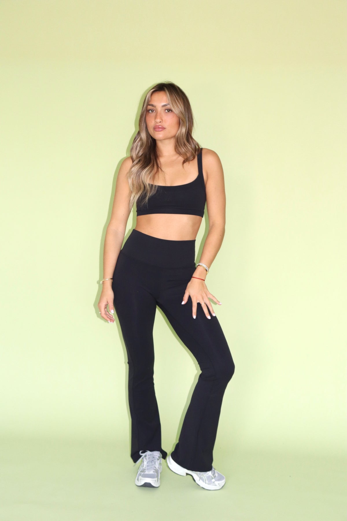 Woman wearing black bell bottom pants with a matching crop top and sneakers