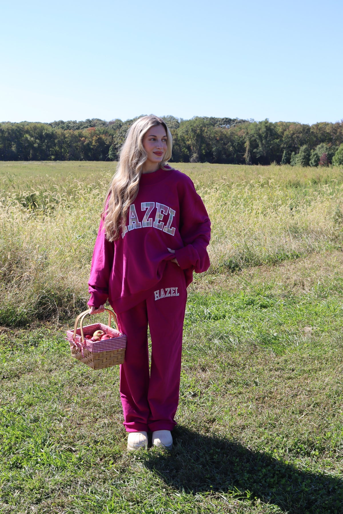 Model wearing burgundy HZL Lottie sweatpants and a matching sweatshirt in a sunny field