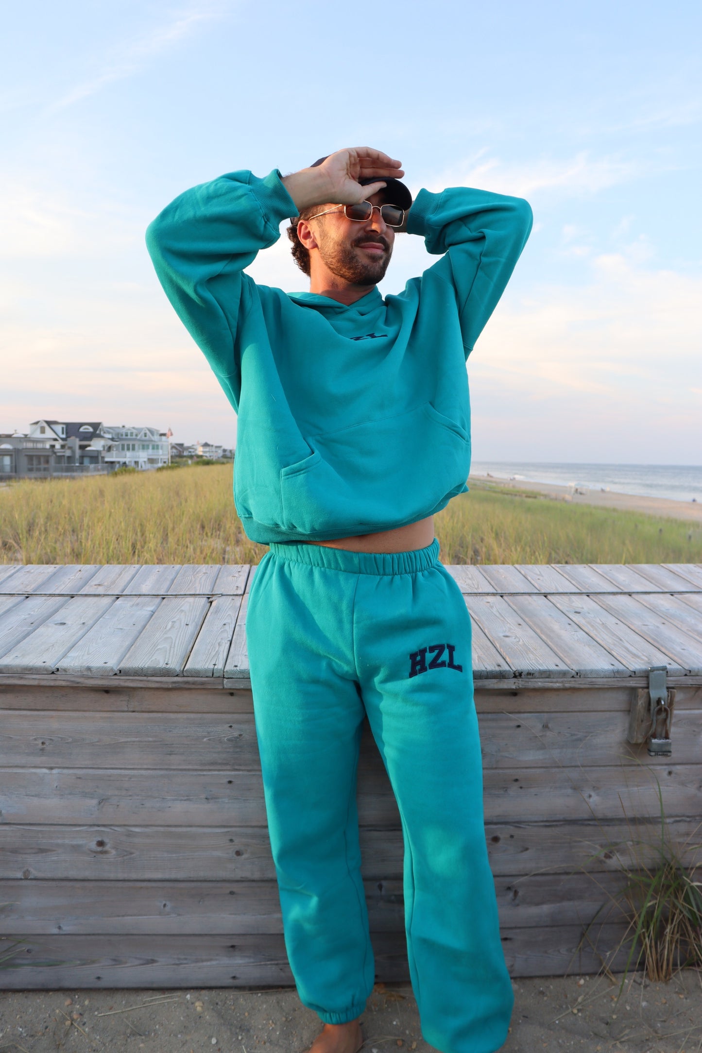 Man wearing teal HZL joggers and a matching sweatshirt on a beach boardwalk