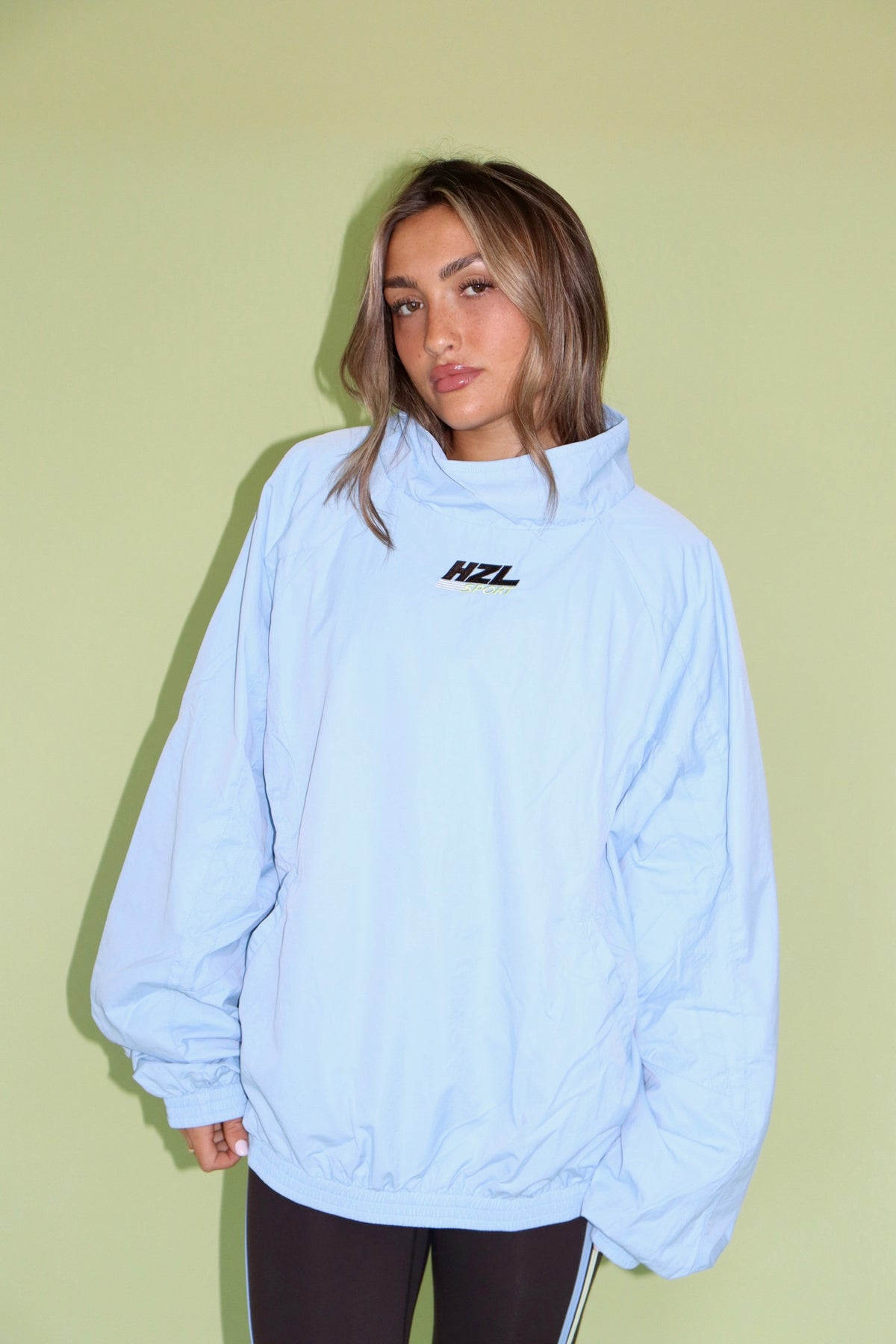 Woman wearing a light blue HZL Sport windbreaker with a high neck and elastic cuffs