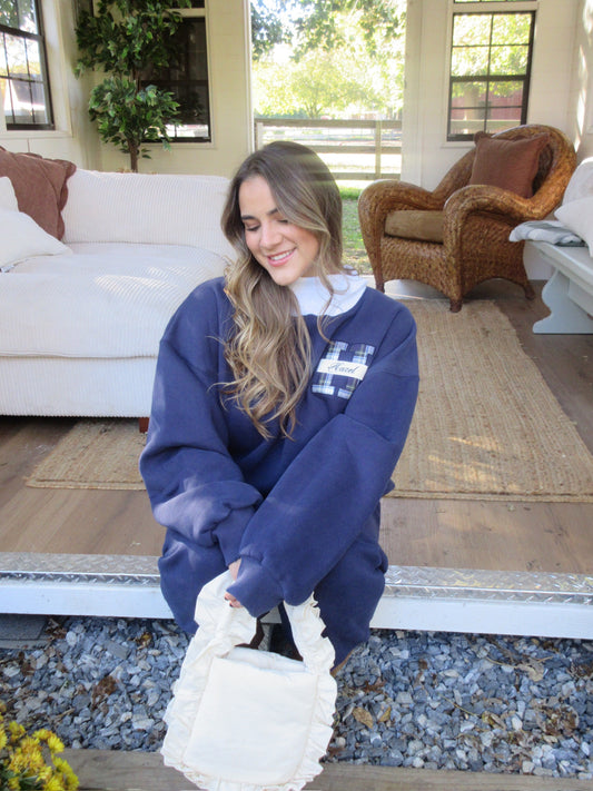 Woman wearing a navy HZL mockneck sweatshirt and carrying a white bag indoors