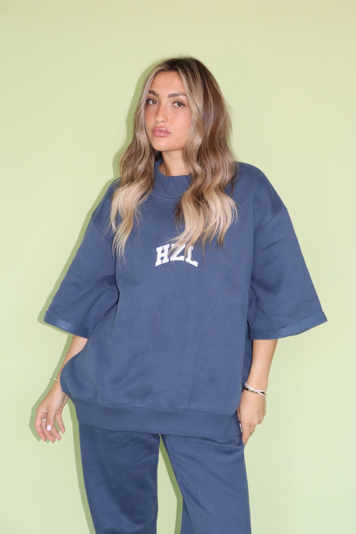 Model wearing a navy HZL short sleeve mockneck top with matching pants and relaxed fit silhouette