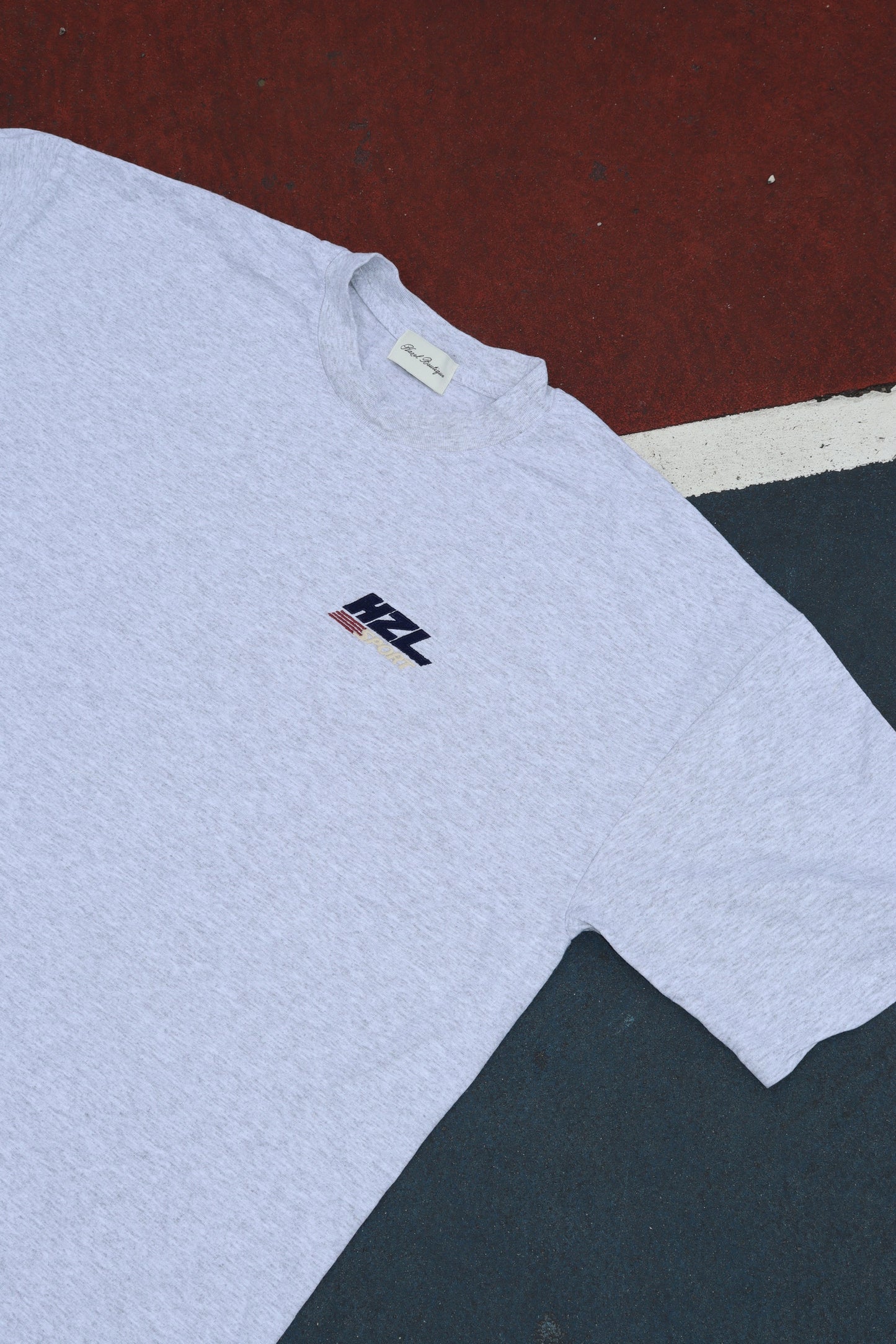 Grey T shirt laid flat with a small HZL logo on the chest
