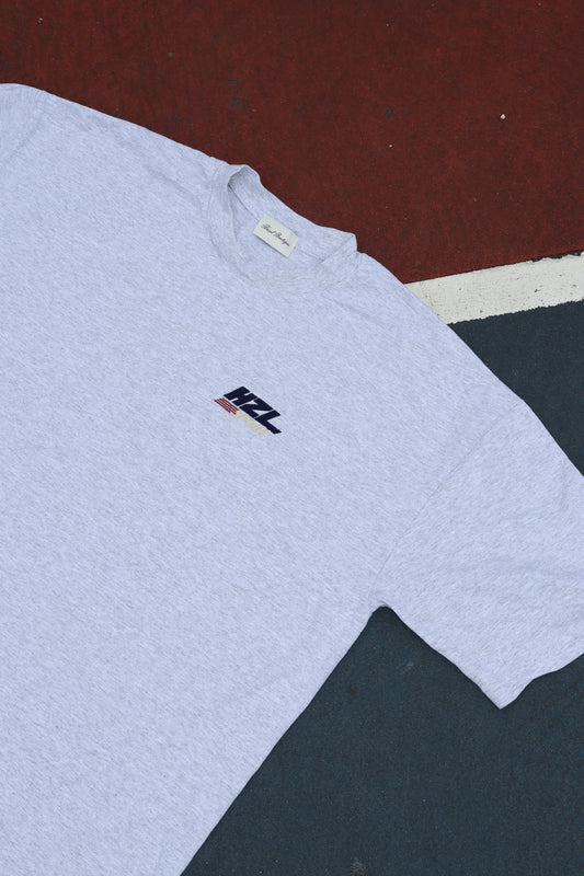 Grey T shirt laid flat with a small HZL logo on the chest
