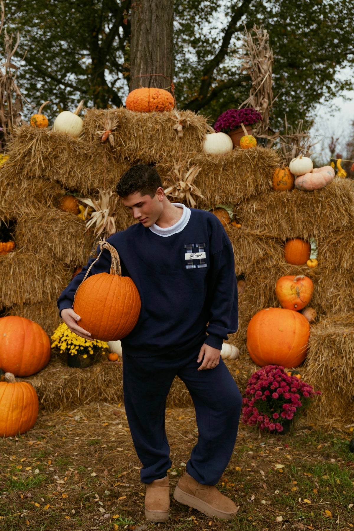 Model wearing navy joggers and a matching sweatshirt among pumpkins and hay bales outdoors