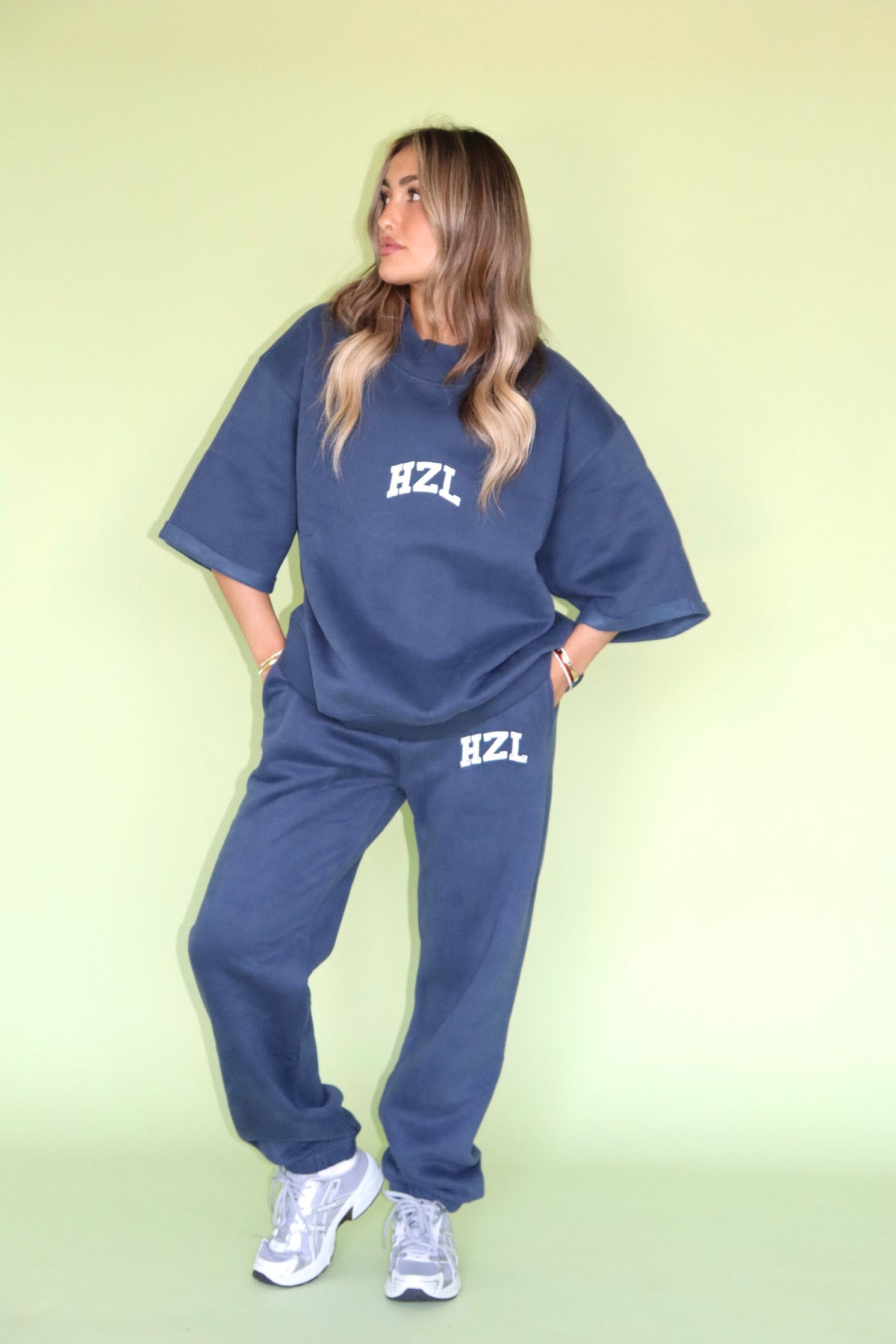 Woman wearing navy HZL joggers with a matching oversized top and white sneakers