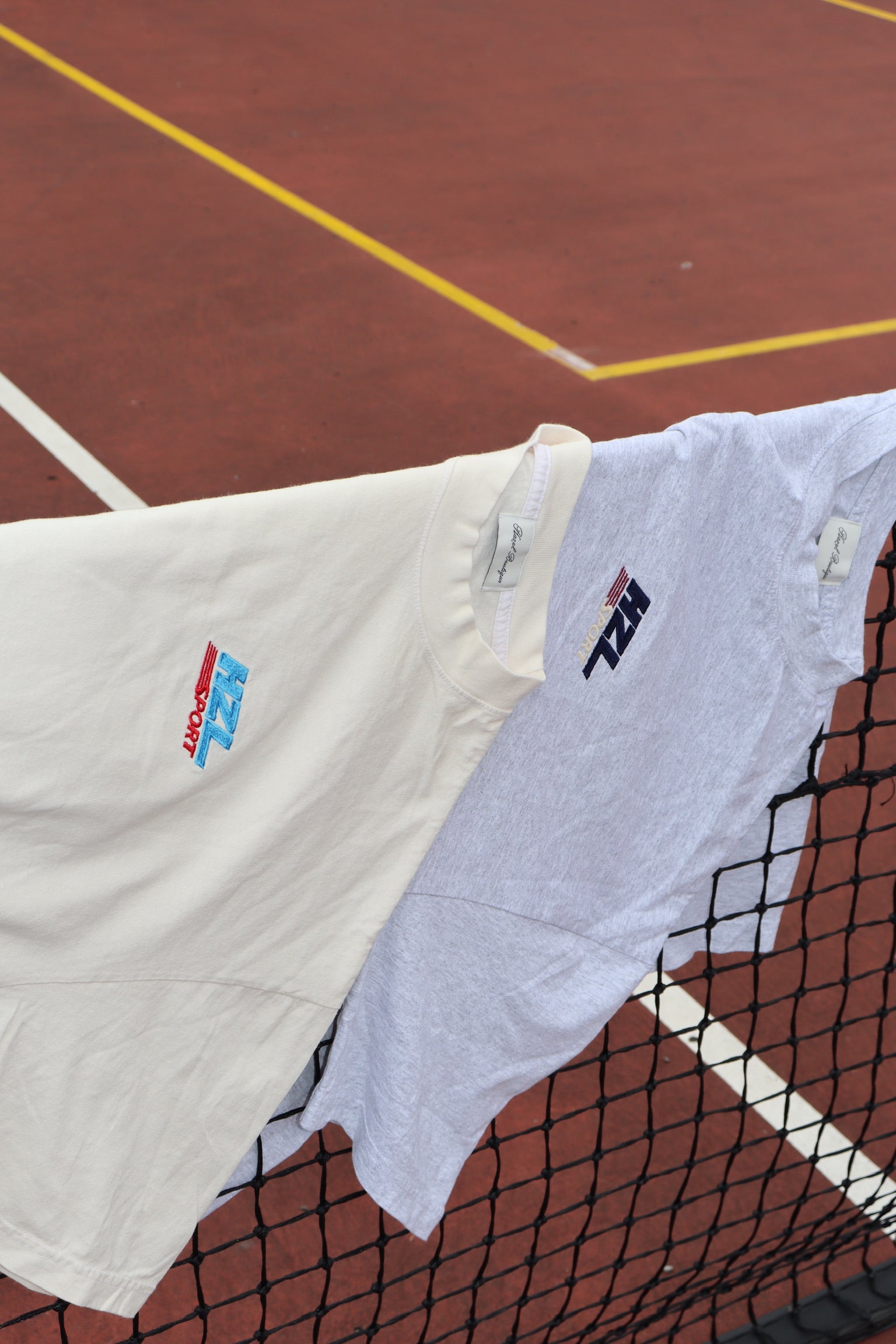 Cream graphic tee draped over a tennis net on an outdoor court