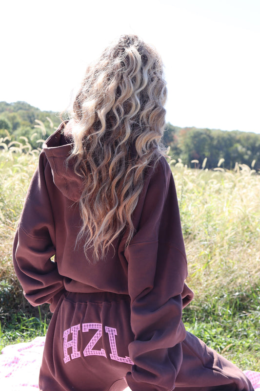 Person wearing burgundy HZL barrel pants outdoors with white lettering on the back