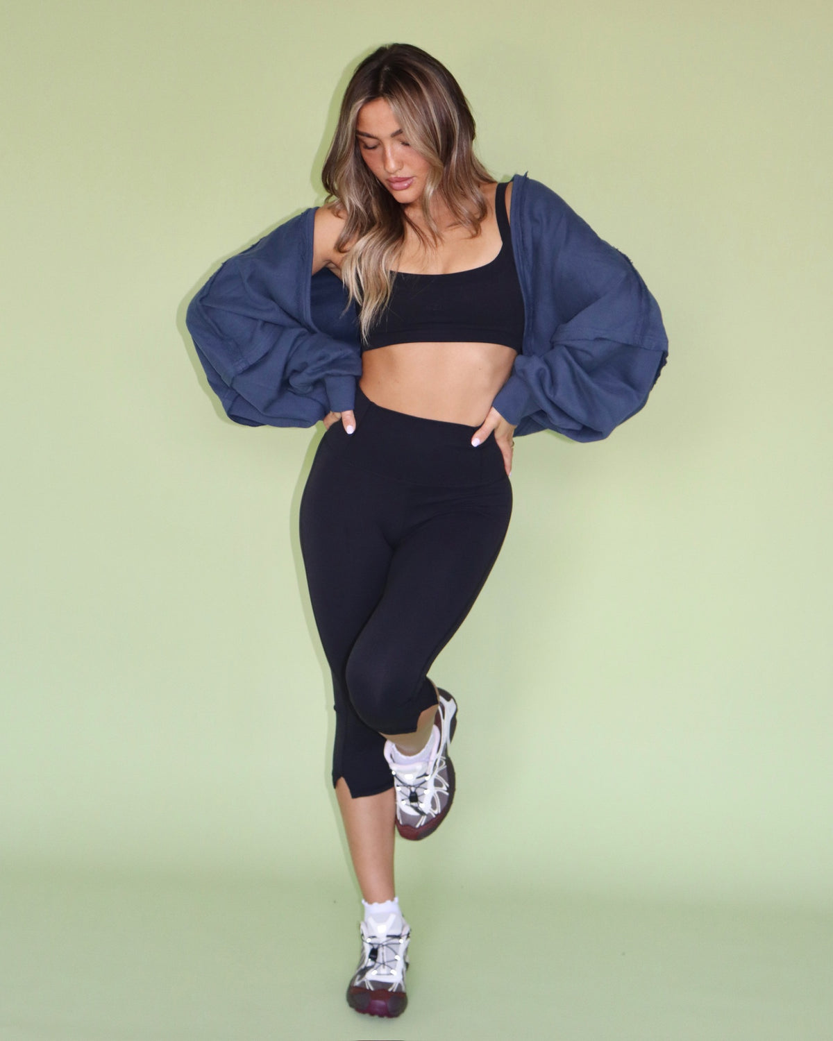 Model wearing a navy warm up shrug with black activewear and sneakers