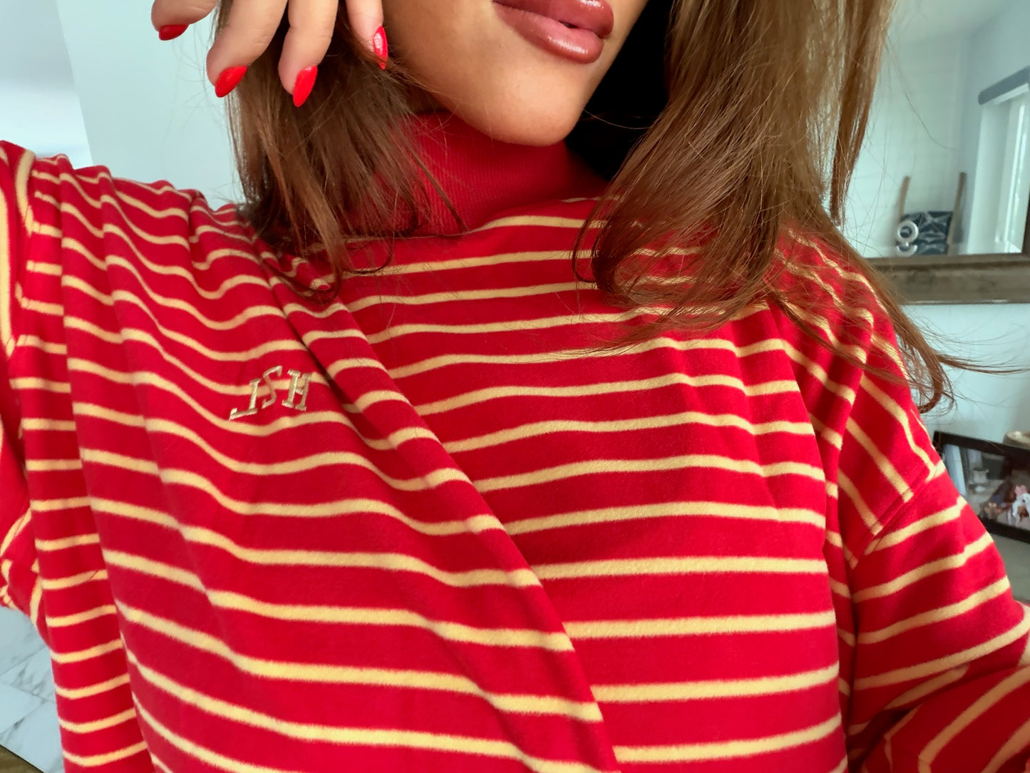Close-up of a woman wearing a red and beige striped mockneck top with a casual, confident vibe.