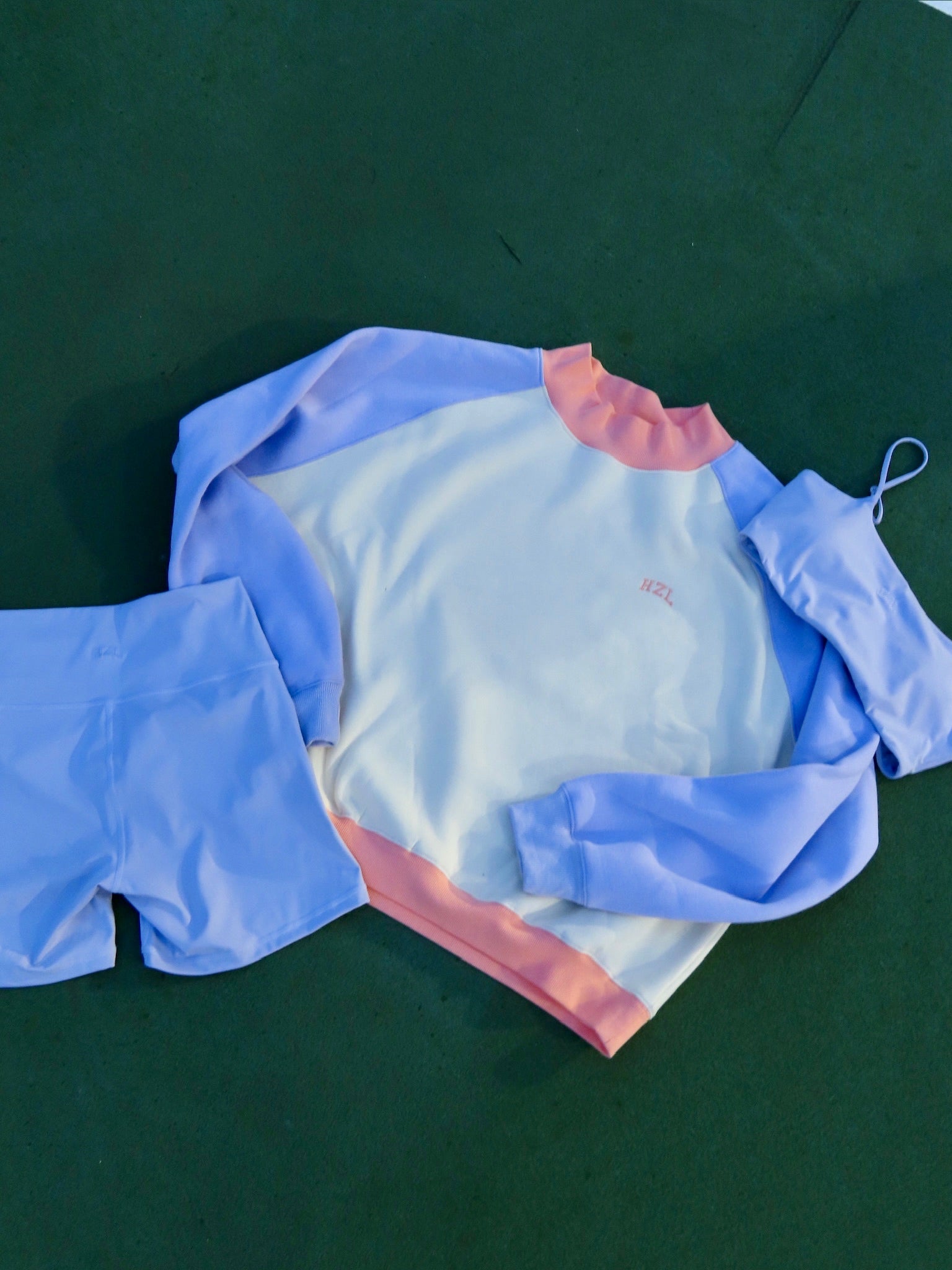 Light purple and white long-sleeve top paired with matching shorts and a swim cap on a dark green surface