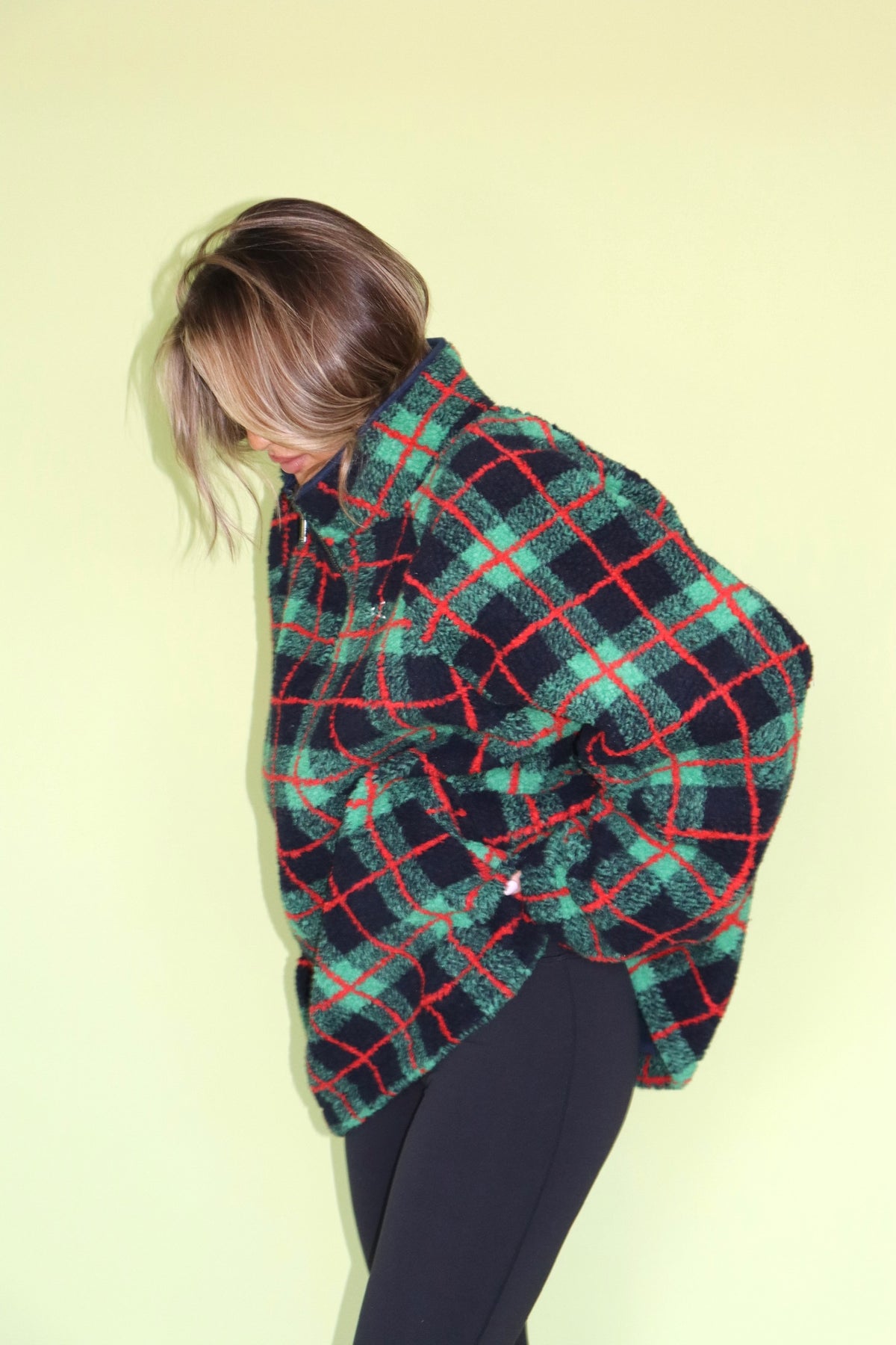 Woman wearing a green and red plaid fleece top with an oversized fit and black leggings