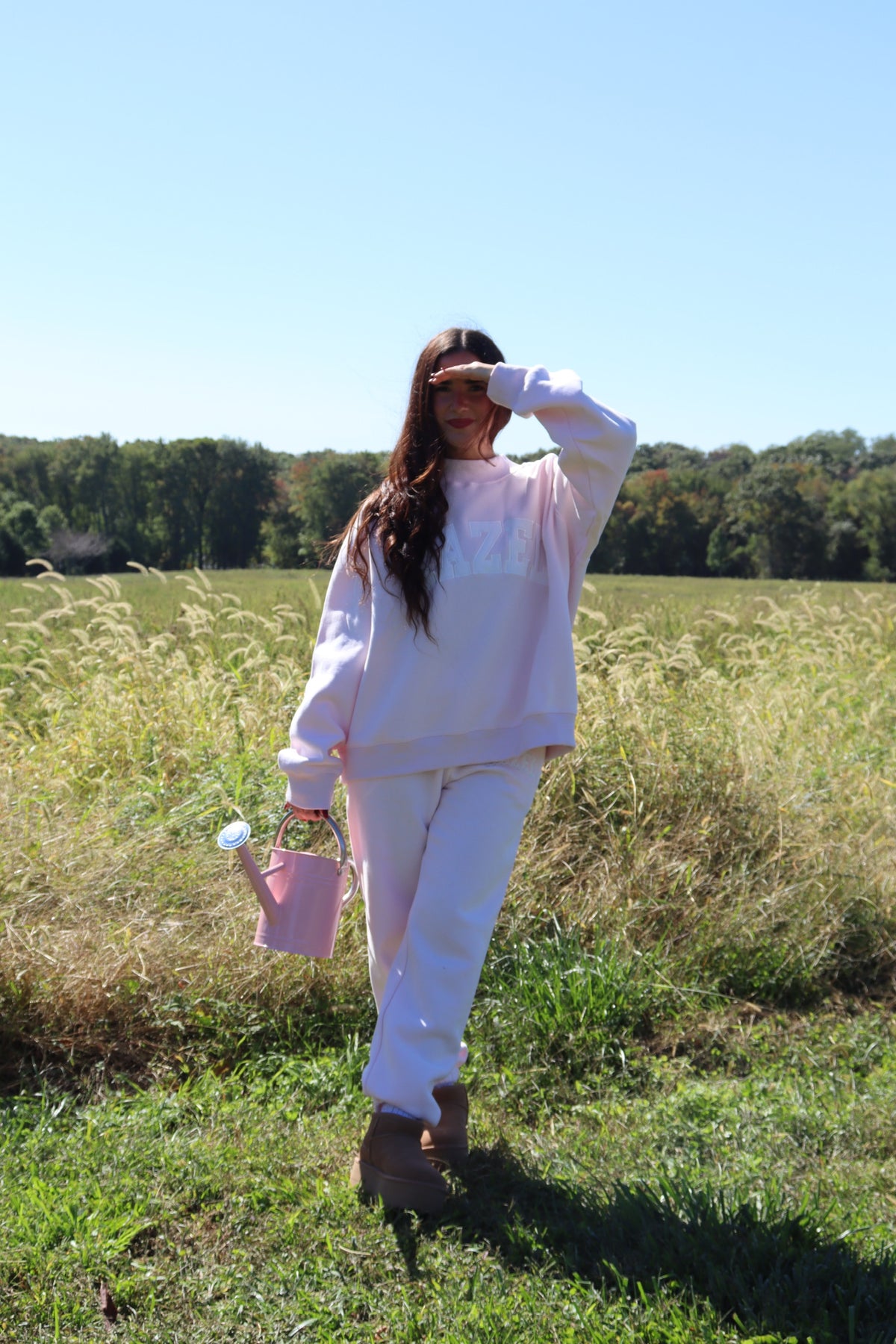 Model wearing light lavender joggers and a matching sweatshirt while walking through a sunny meadow