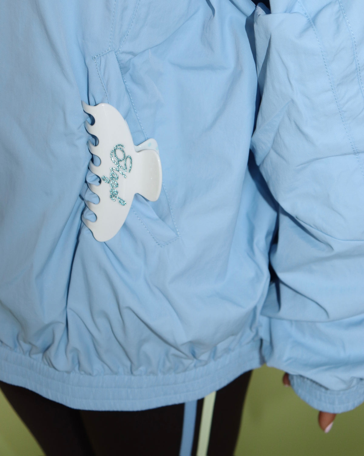 White polka dot claw clip with blue floral detailing attached to a light blue jacket