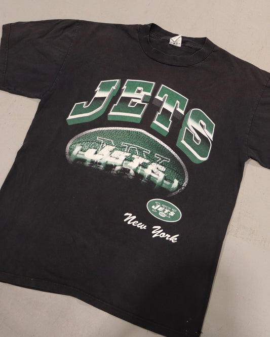 Black vintage New York Jets tee with green and white lettering and football helmet graphic laid flat