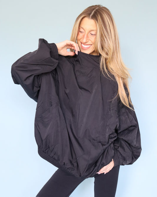 Woman wearing a black oversized windbreaker with elastic cuffs and hem