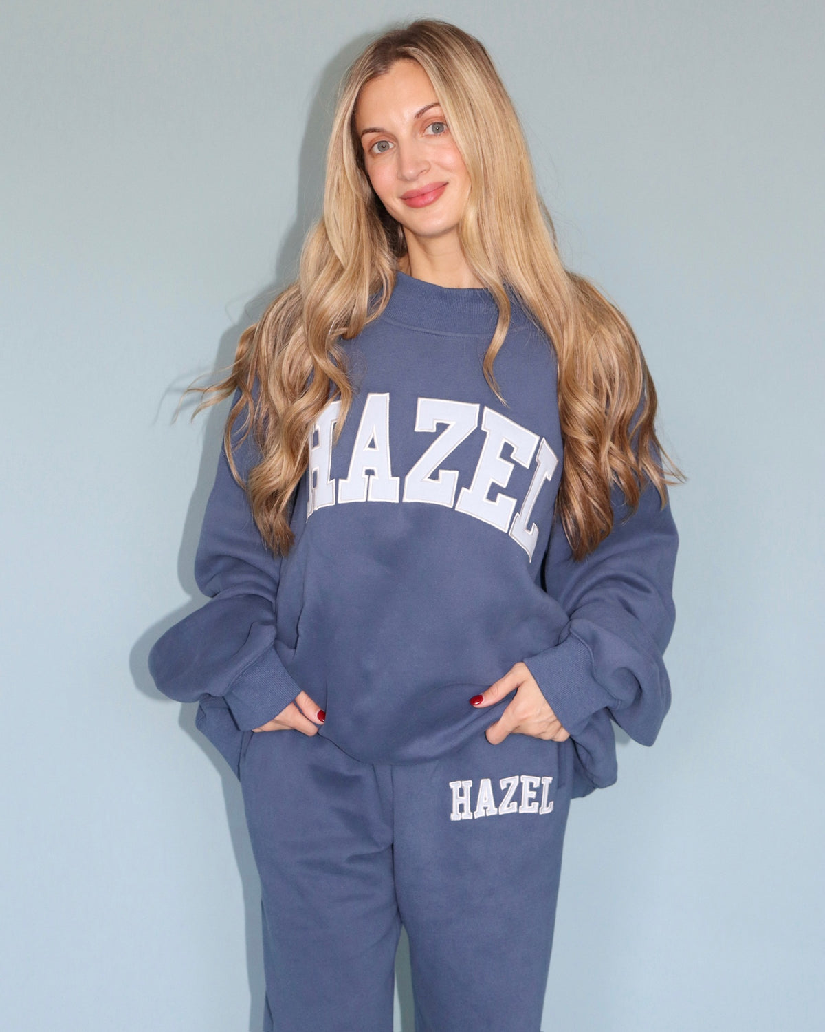 Model wearing a blue Hazel sweatshirt and matching joggers with white lettering