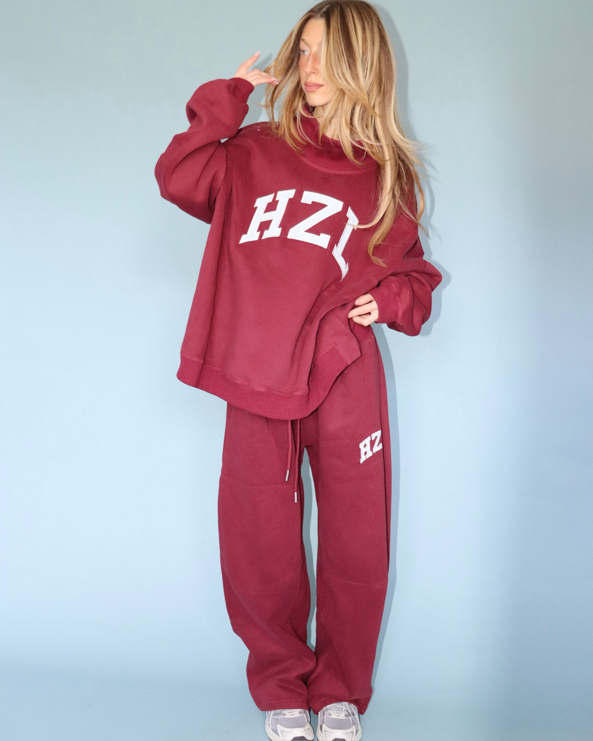 Model wearing burgundy barrel pants with a matching oversized sweatshirt and sneakers