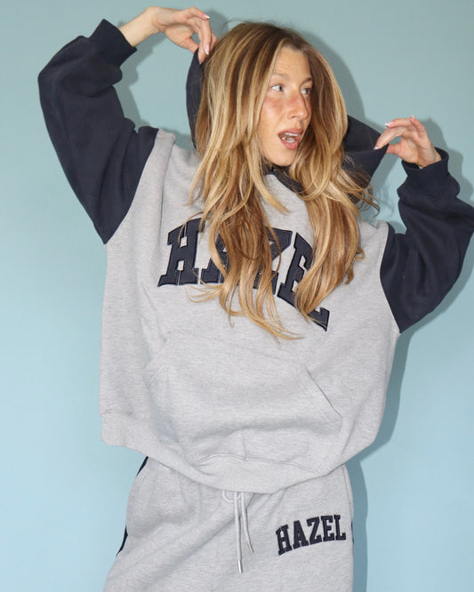 Model wearing a gray Hazel sweatshirt with navy sleeves and matching sweatpants