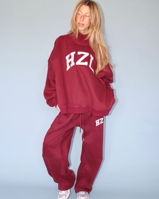Woman wearing a burgundy HZL sweatshirt with matching relaxed barrel leg pants and white sneakers