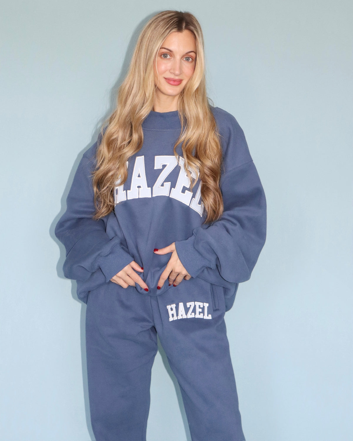 Model wearing a blue HZL mockneck sweatshirt and matching jogger pants with Hazel lettering